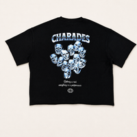 A black short-sleeve graphic T-shirt laid flat against a light beige background. The shirt features a large metallic silver and blue 'CHARADES' logo at the chest, a cluster of stylized blue-and-silver skull faces in the center, and smaller white text and a small globe logo near the hem.
